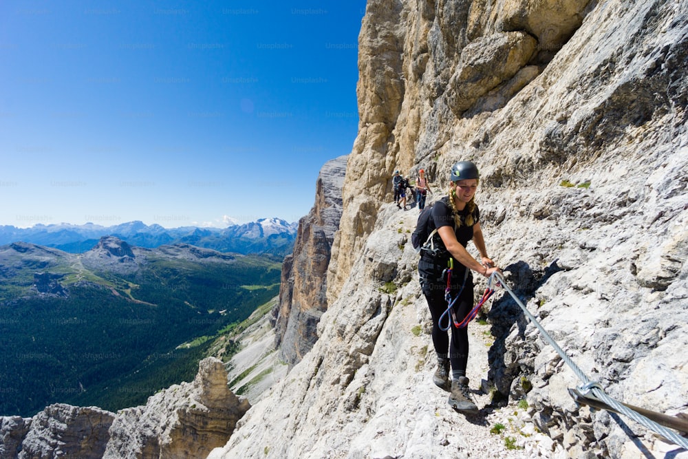 several young mountain climbers on very exposed Via Ferrata in Alta Badia in the Italian Dolomites
