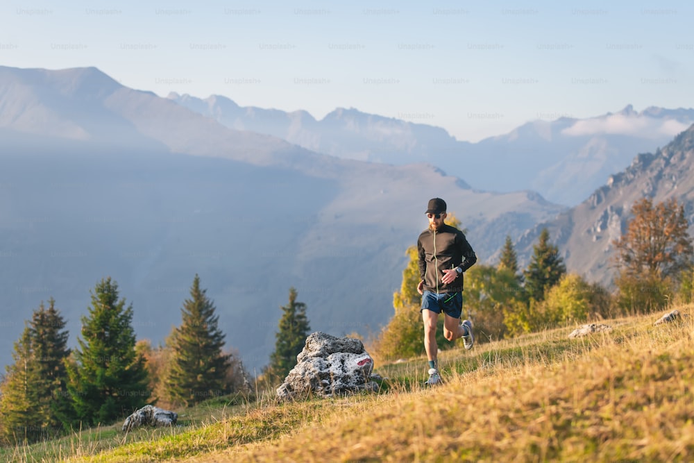 Athlete man runs through mountain meadows in autumn