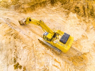 Aerial view of a excavator in open cast mine or on construction site. Heavy industry from above. Industrial photography from drone.