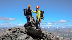 두 명의 남성 산악인이 생모리츠 근처 스위스 알프스의 높은 봉우리 정상에서 서로를 축하하고 있다
