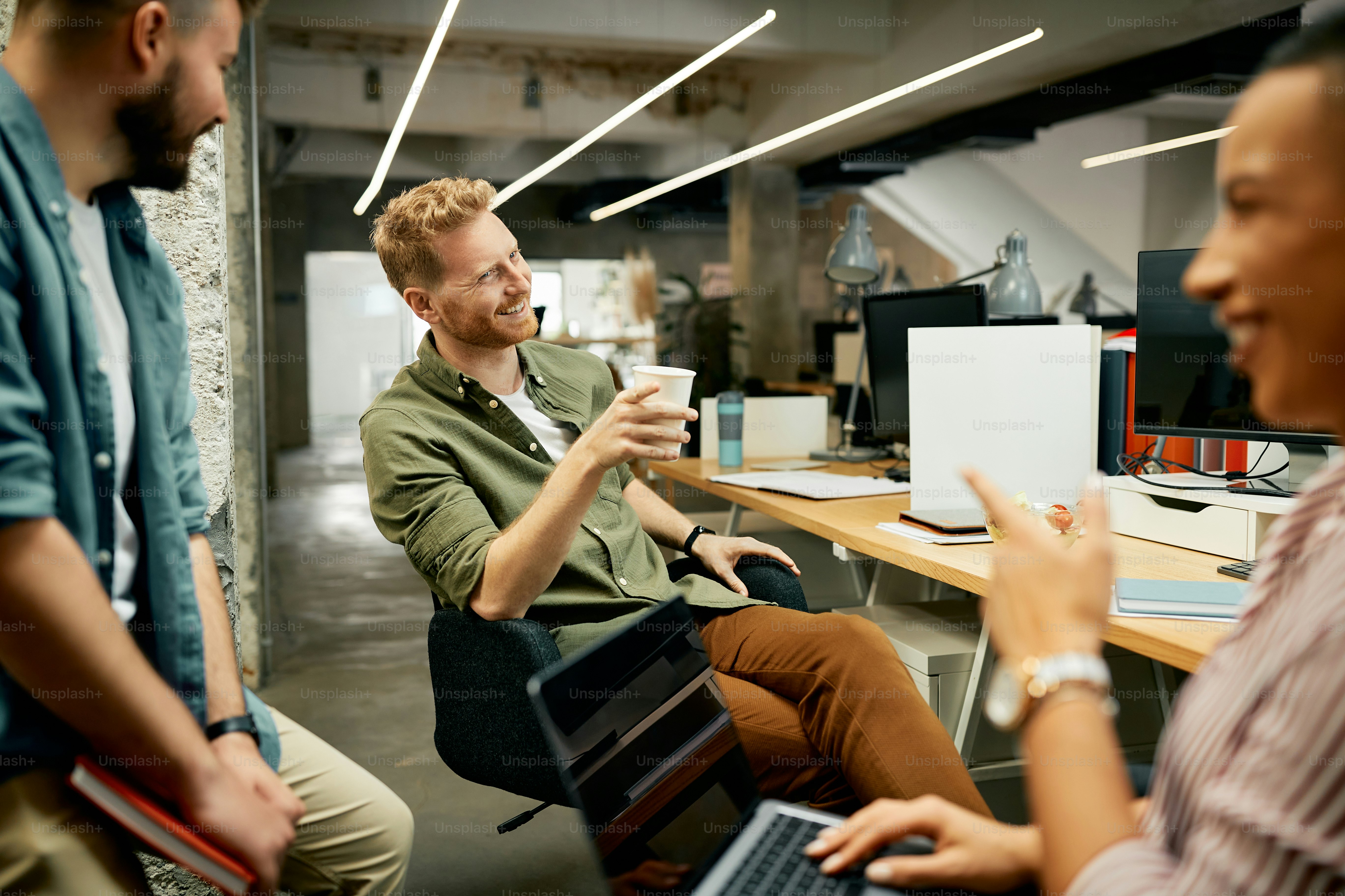 Happy businessman and his coworkers having while while communicating during a break at work