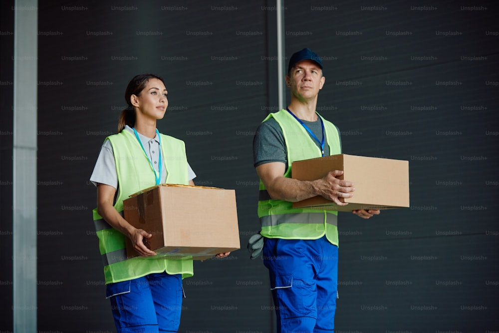 Warehouse workers carrying packagers while working at storage compartment.