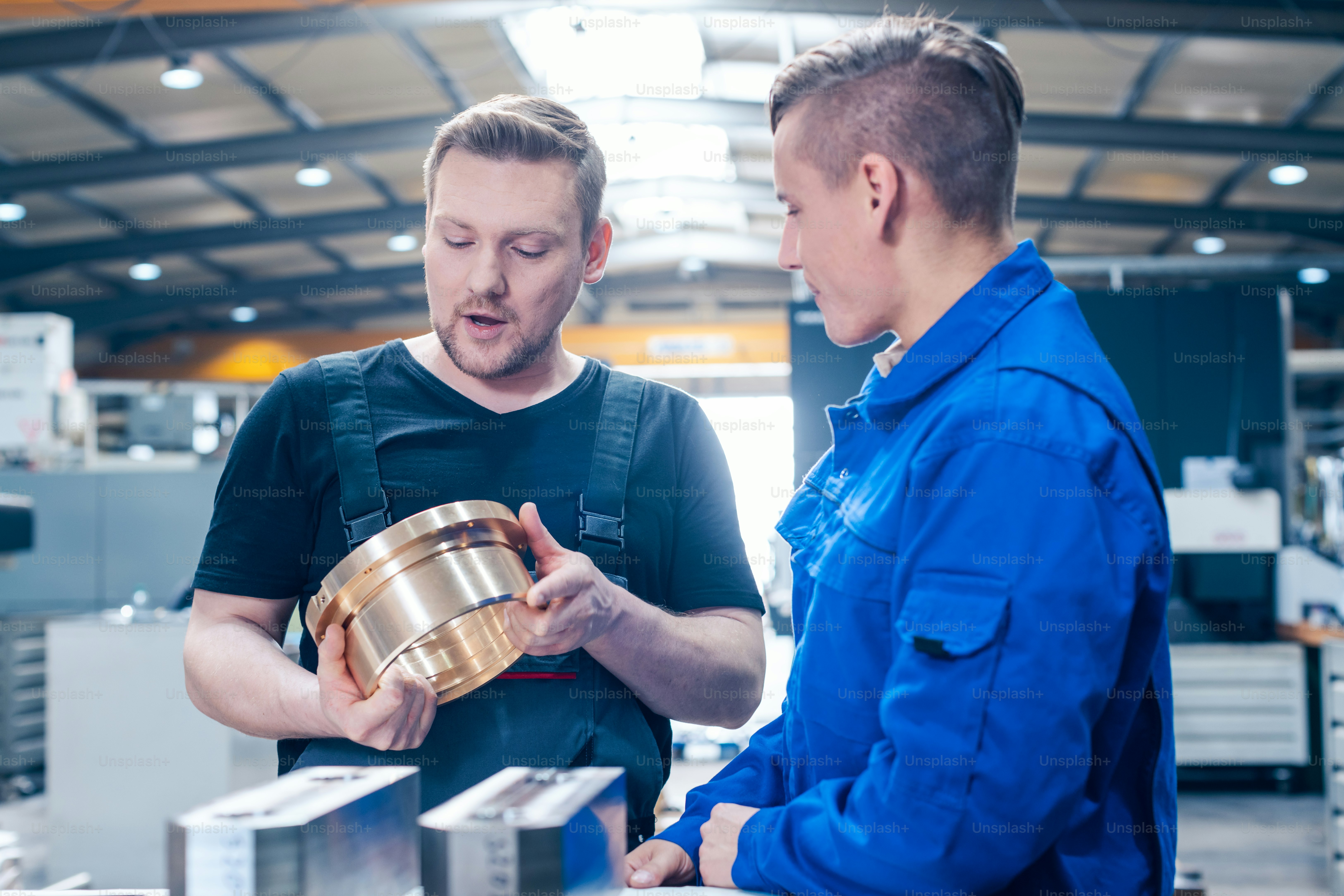 Skillful master discussing a workpiece with his apprentice or trainee