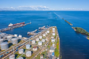 Vista aerea del grande terminale di carico dell'olio portuale con grandi serbatoi di stoccaggio. Consegna di merci alla rinfusa e il canale marittimo che va in mare