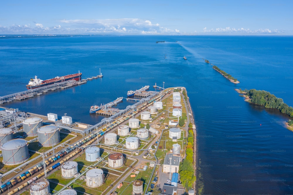 Aerial view large port oil loading terminal with large storage tanks. Delivery of bulk cargo and the sea channel going to sea