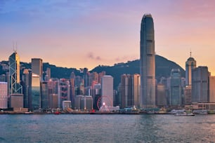 홍콩 스카이라인 도시 풍경 시내의 고층 빌딩이 저녁에는 빅토리아 항구 위로 올라가고 일몰에 정크 관광 페리 보트가 극적인 하늘을 감상할 수 있습니다. 홍콩, 중국