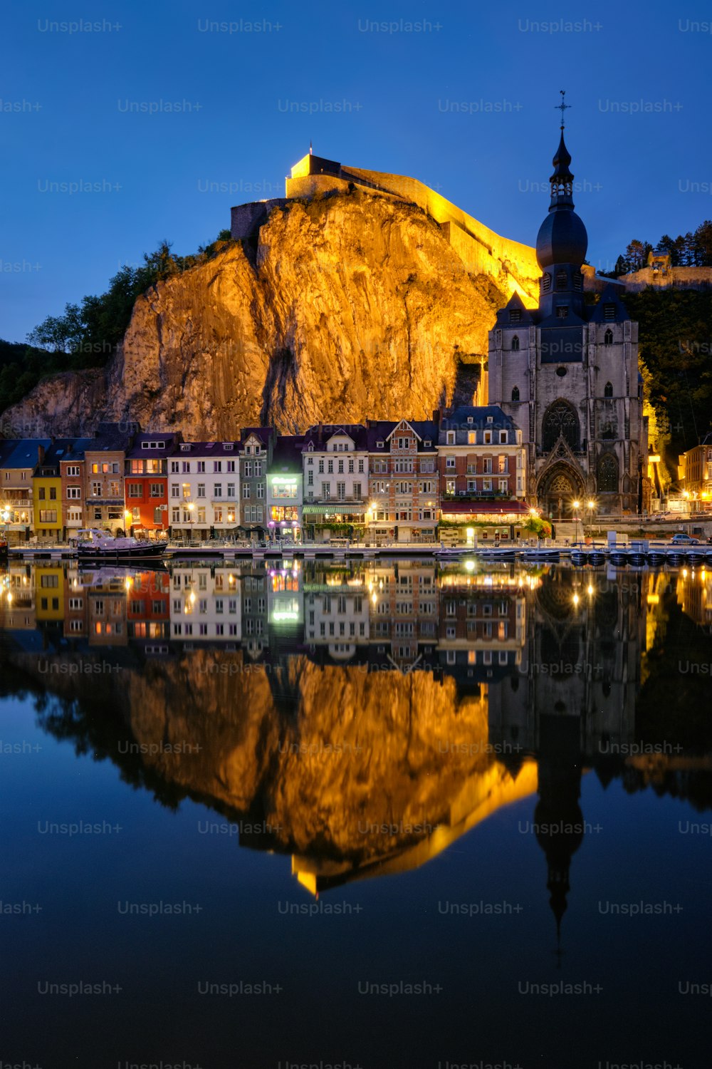 Night view of Dinant town, Collegiate Church of Notre Dame de Dinant over River Meuse and Pont Charles de Gaulle bridge and Dinant Citadel illuminated in the evening. Dinant,  Belgium