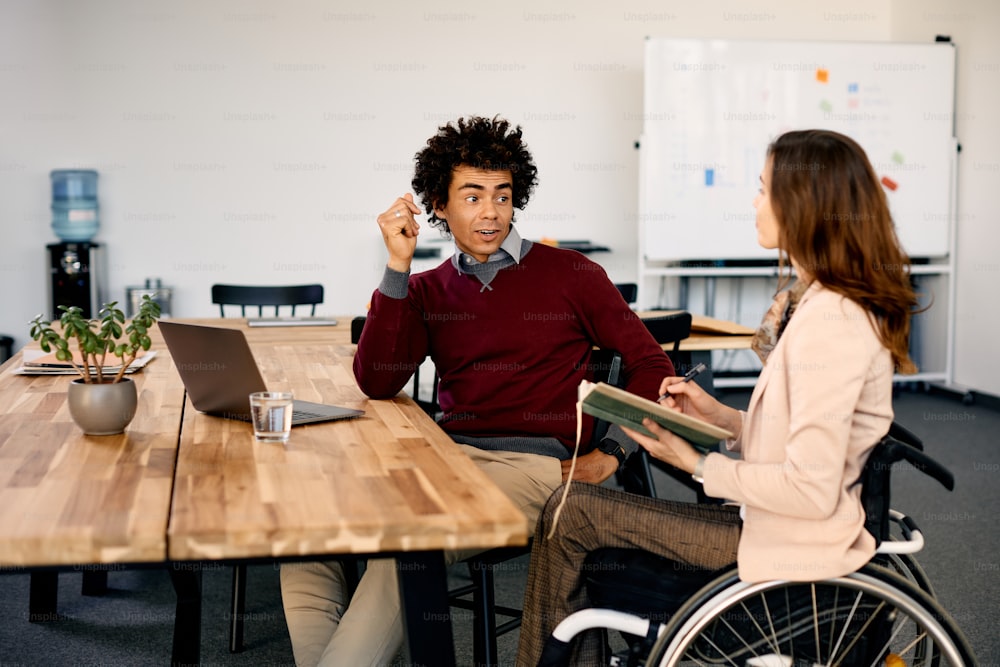 아프리카계 미국인 기업가가 사무실에서 회의 중 휠체어를 탄 여성 동료와 의사소통을 하고 있다.