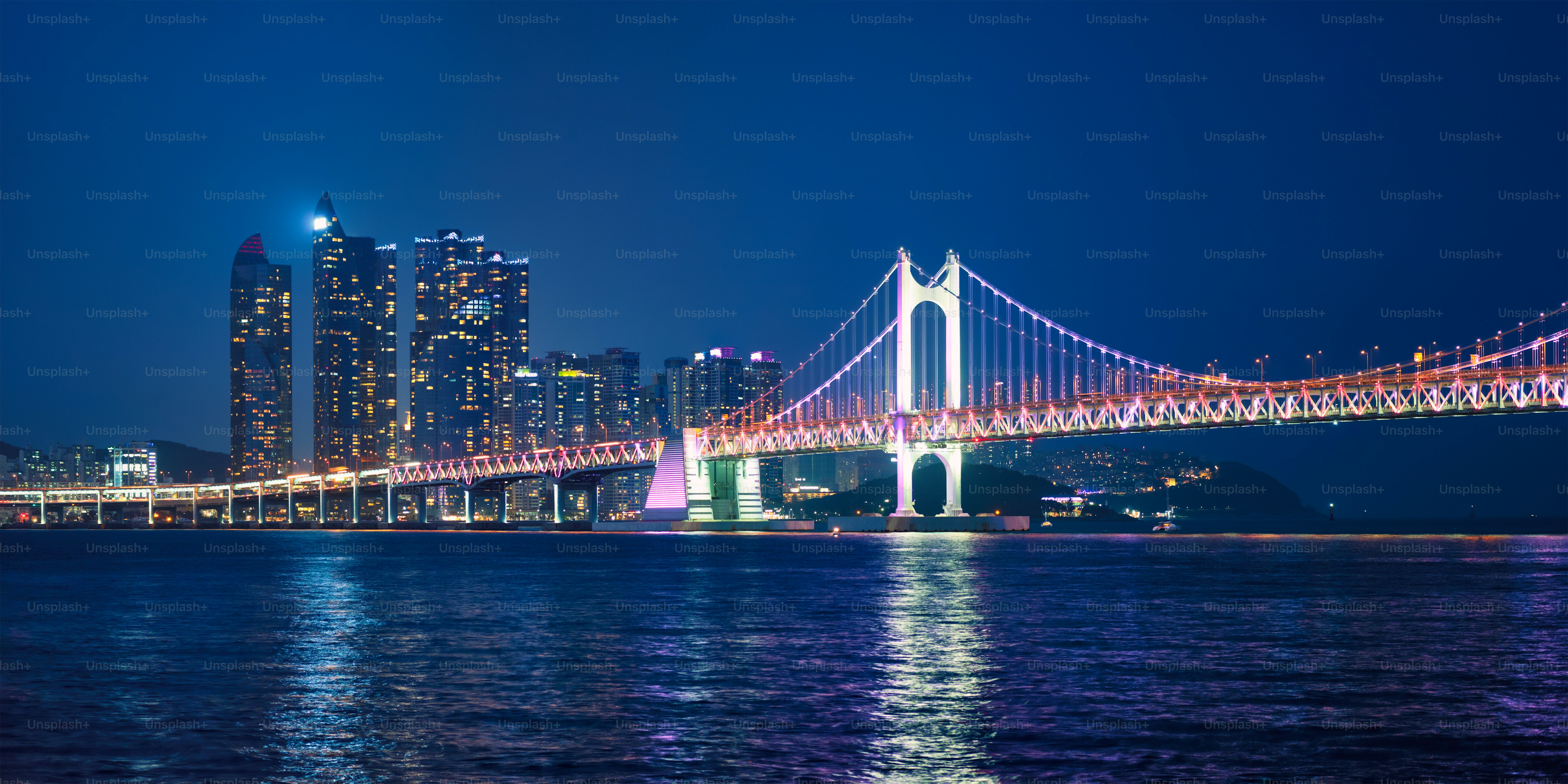 Panorama of Gwangan Bridge and skyscrapers illuminated in the night. Busan, South Korea