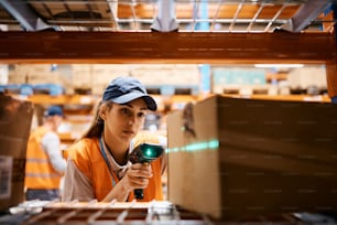 Female worker using bar code reader while scanning packages in a warehouse.