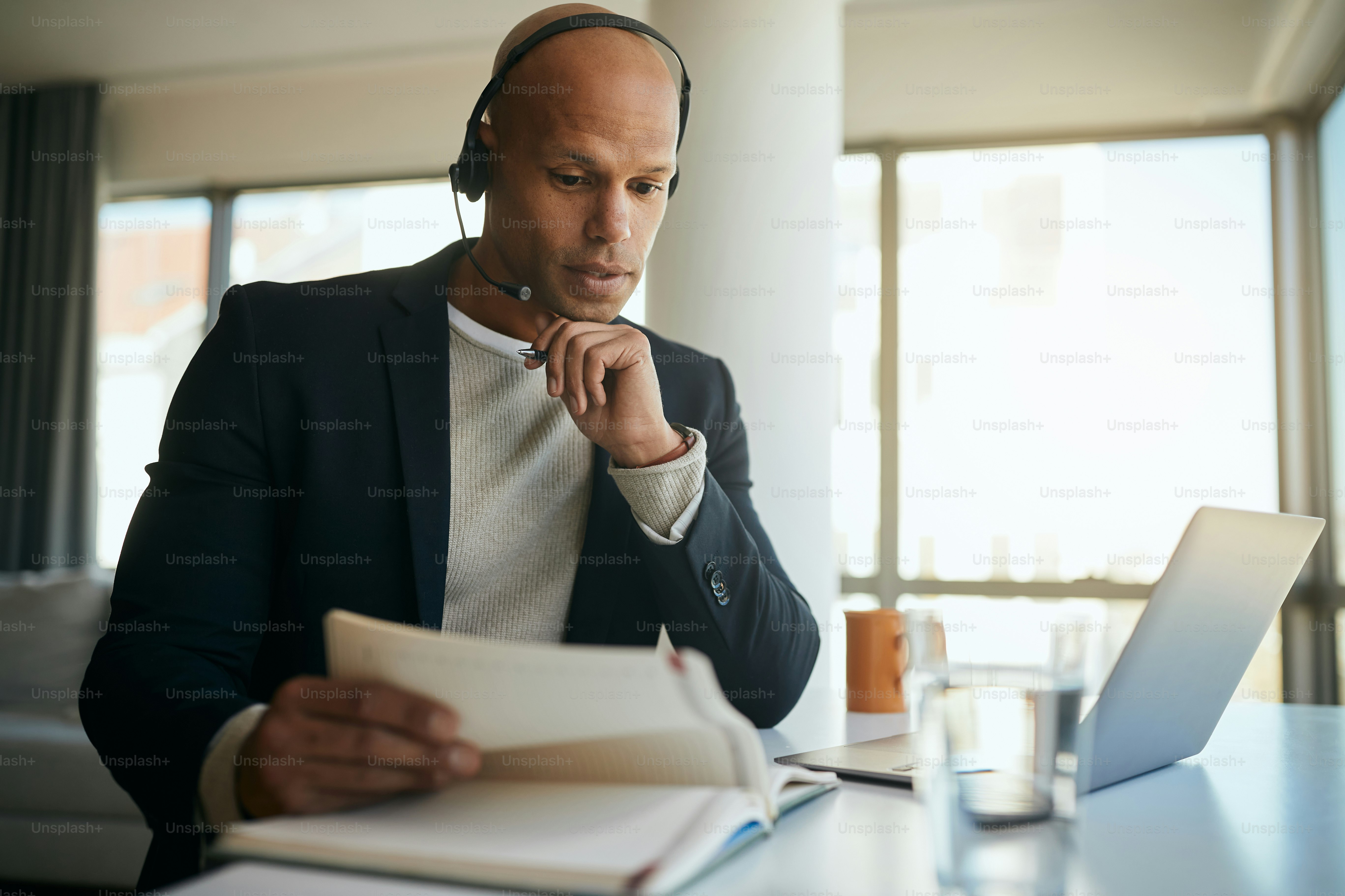 African American businessman going through paperwork during conference call via laptop in the office.