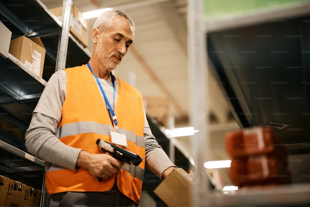 Mature worker scanning labels on cardboard boxes at distribution warehouse.
