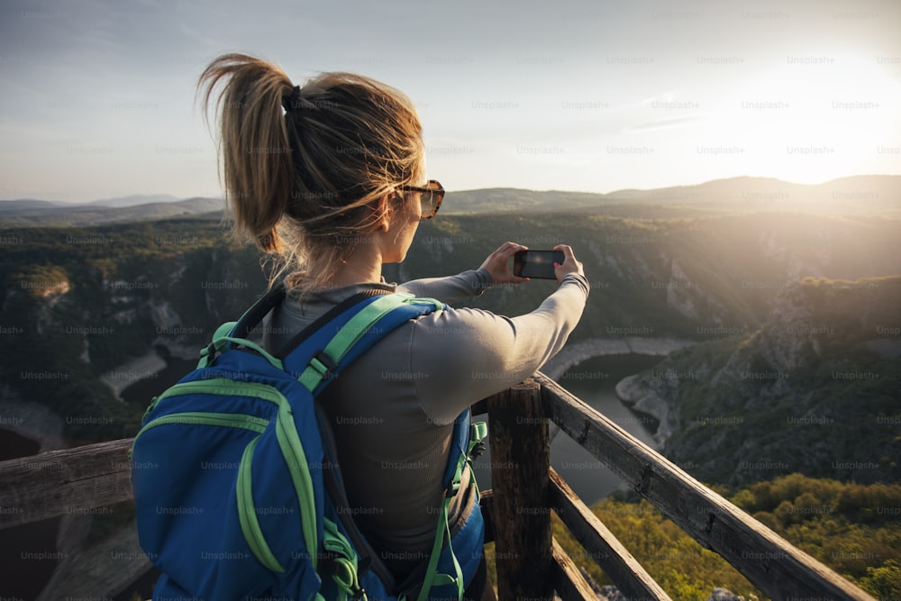 협곡 관점에서 스마트폰으로 사진을 찍는 젊은 여성 등산객.