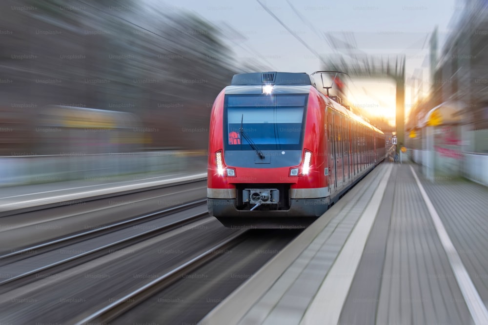 Gare avec train de banlieue à grande vitesse de locomotive de tête avec effet de flou de mouvement.