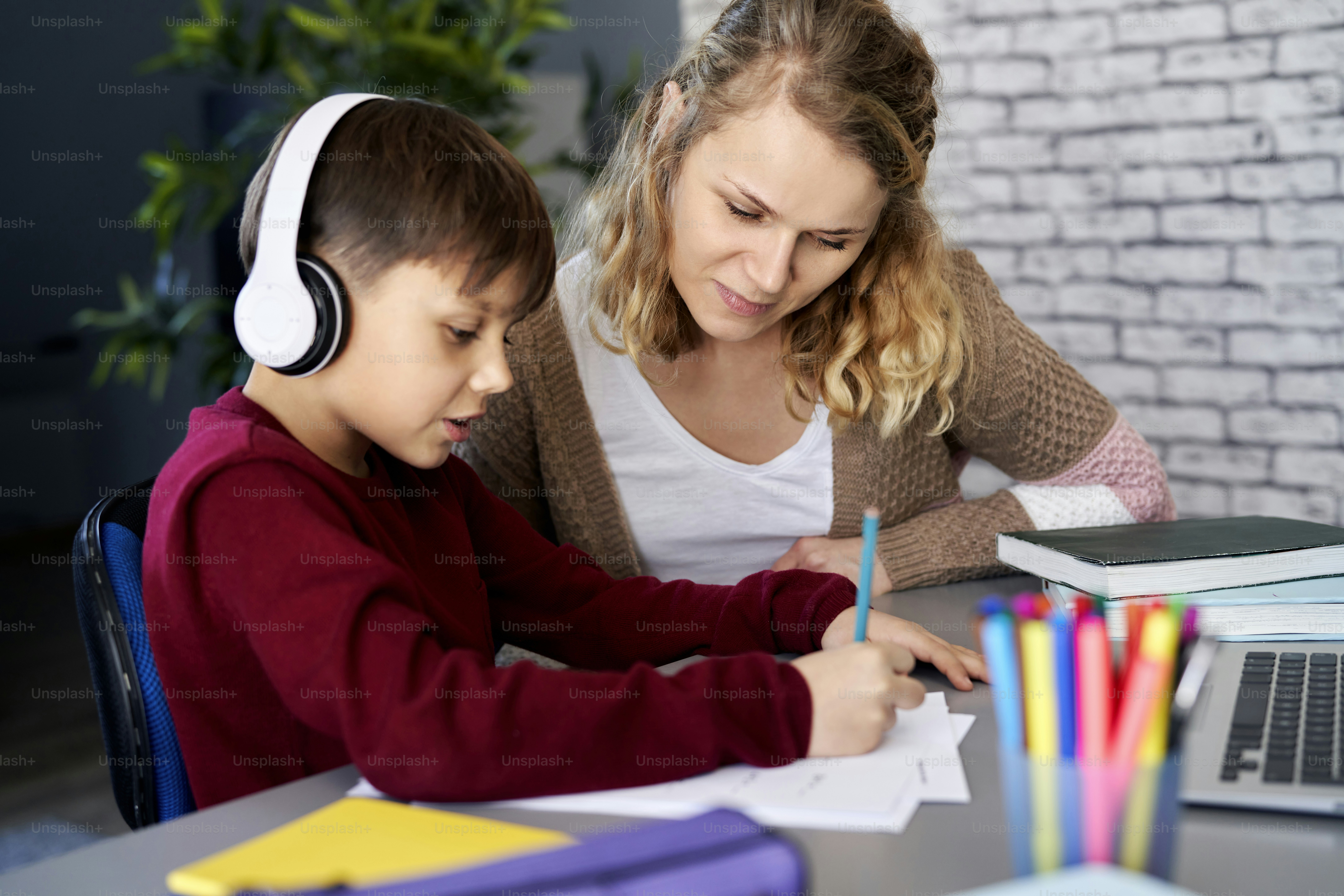 Boy happily doing homework with his mom at home