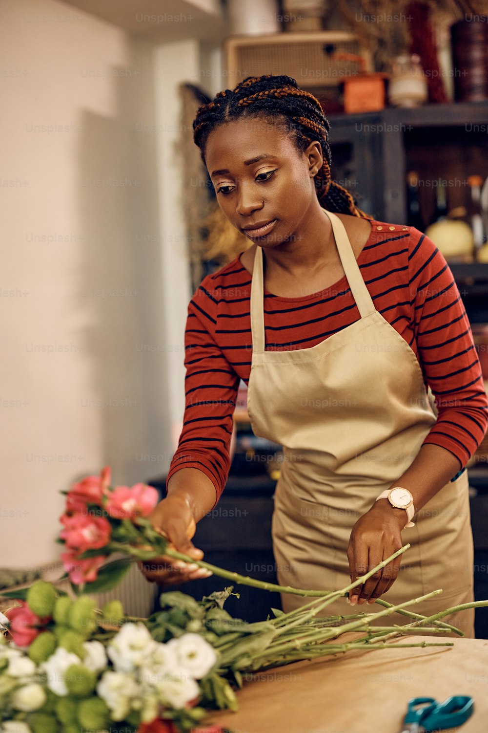 그녀의 꽃집에서 신선한 꽃을 꽂는 아프리카계 미국인 꽃집.