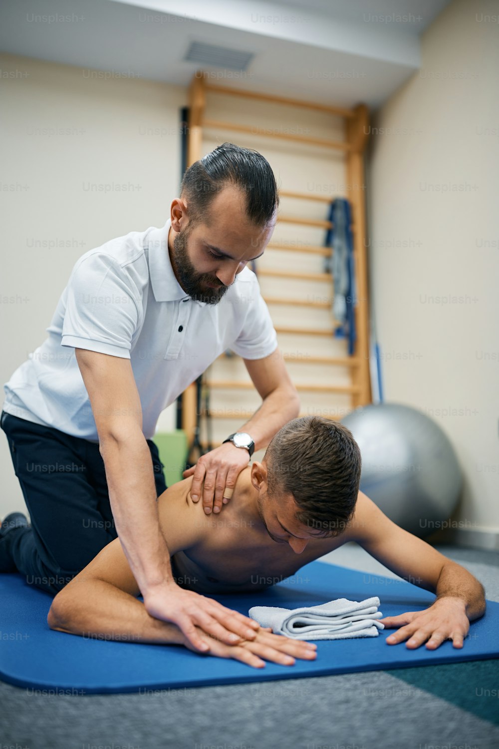 Young sportsman having chiropractic treatment with physical therapist at rehabilitation center.