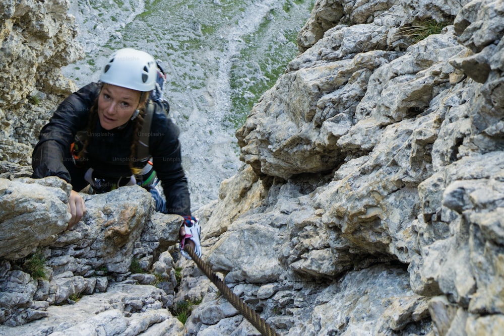 alpinista feminina atraente nas Dolomitas da Itália na íngreme e difícil Poessnecker Via Ferrata