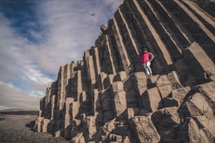 Il viaggiatore viaggia verso una formazione rocciosa vulcanica unica sulla spiaggia di sabbia nera dell'Islanda situata vicino al villaggio di Vik i myrdalin, nel sud dell'Islanda. Le rocce colonnari esagonali attirano i turisti che visitano l'Islanda.
