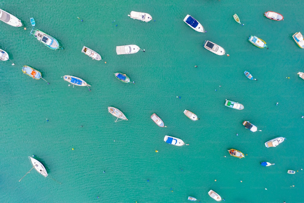 Barche colorate dagli occhi tradizionali nel porto del villaggio di pescatori mediterraneo, vista aerea Marsaxlokk, Malta