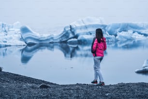 Woman traveler travels to Jokulsarlon beautiful glacial lagoon in Iceland. Jokulsarlon is a famous destination in Vatnajokull National Park, southeast Iceland, Europe. Cold winter ice nature.