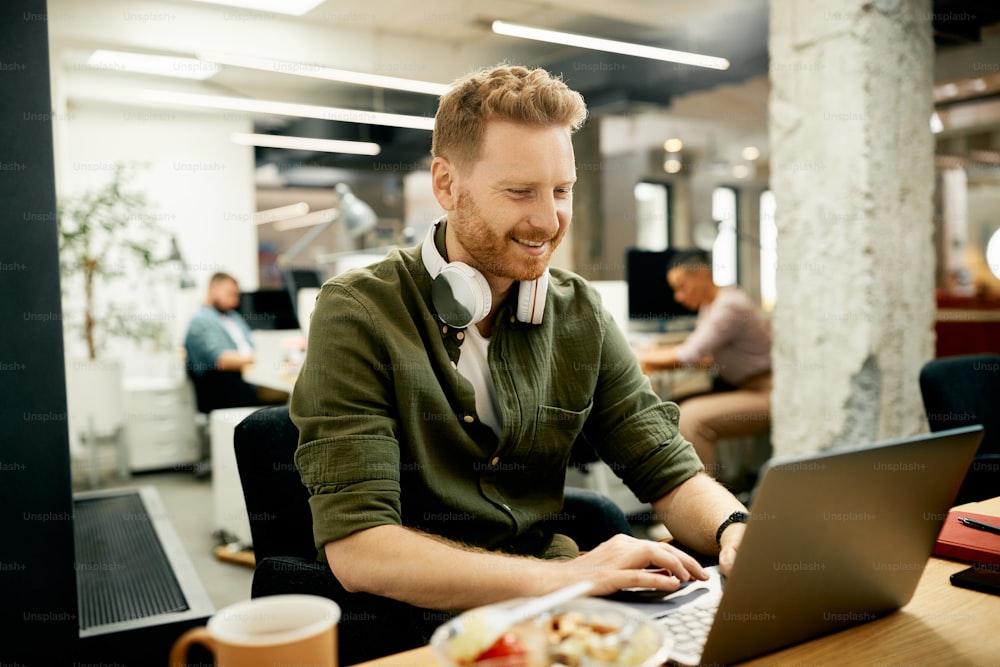 Imprenditore felice che usa il laptop mentre lavora in un ufficio aziendale.