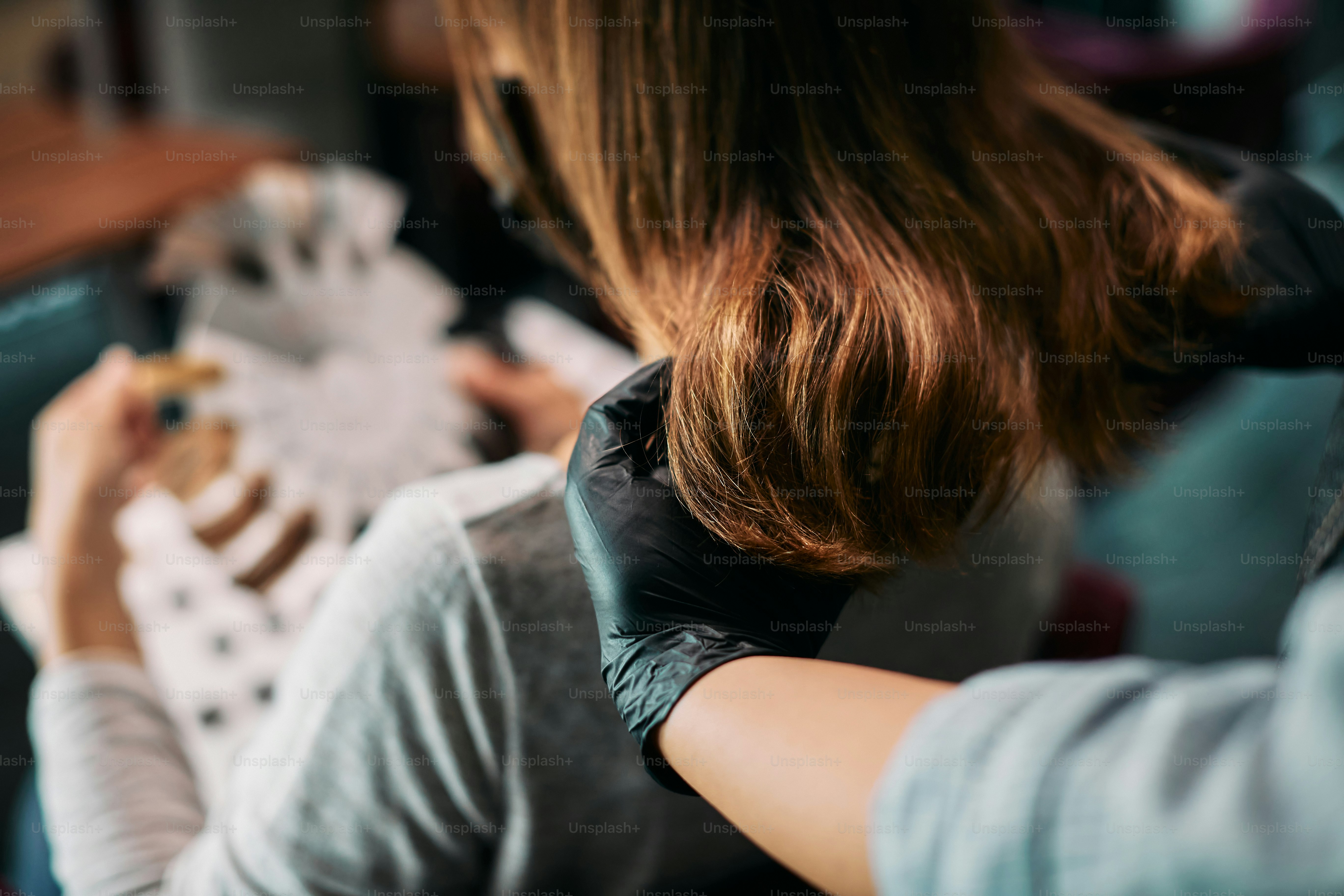 Primo piano del parrucchiere che guarda i capelli della donna prima della colorazione dei capelli.