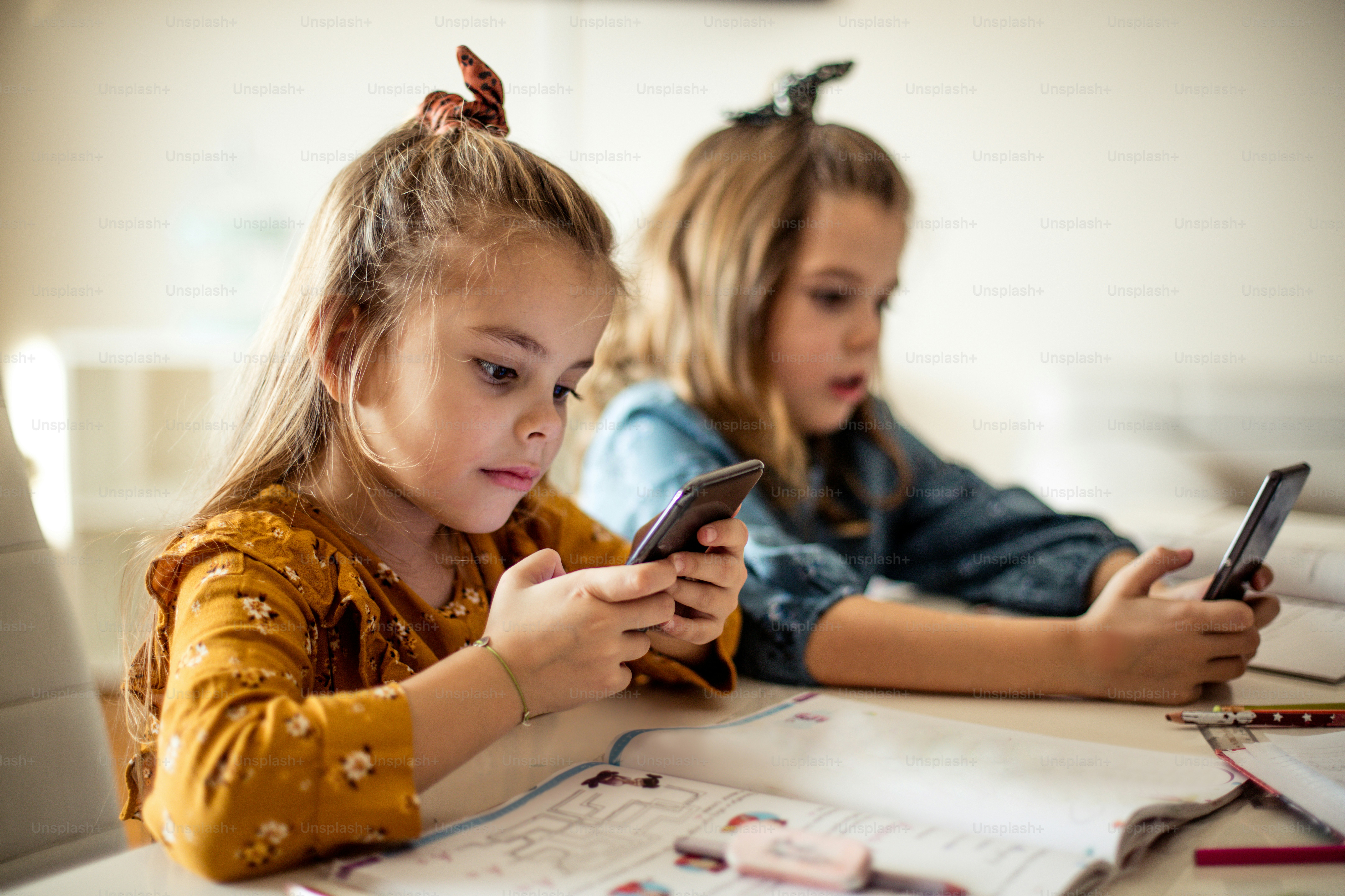Le téléphone est plus intéressant que les tâches. Deux petites écolières utilisant un téléphone intelligent.