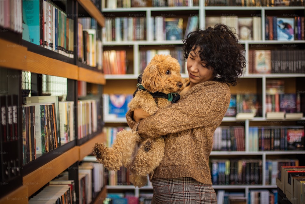 Happy woman with her dog in library.
