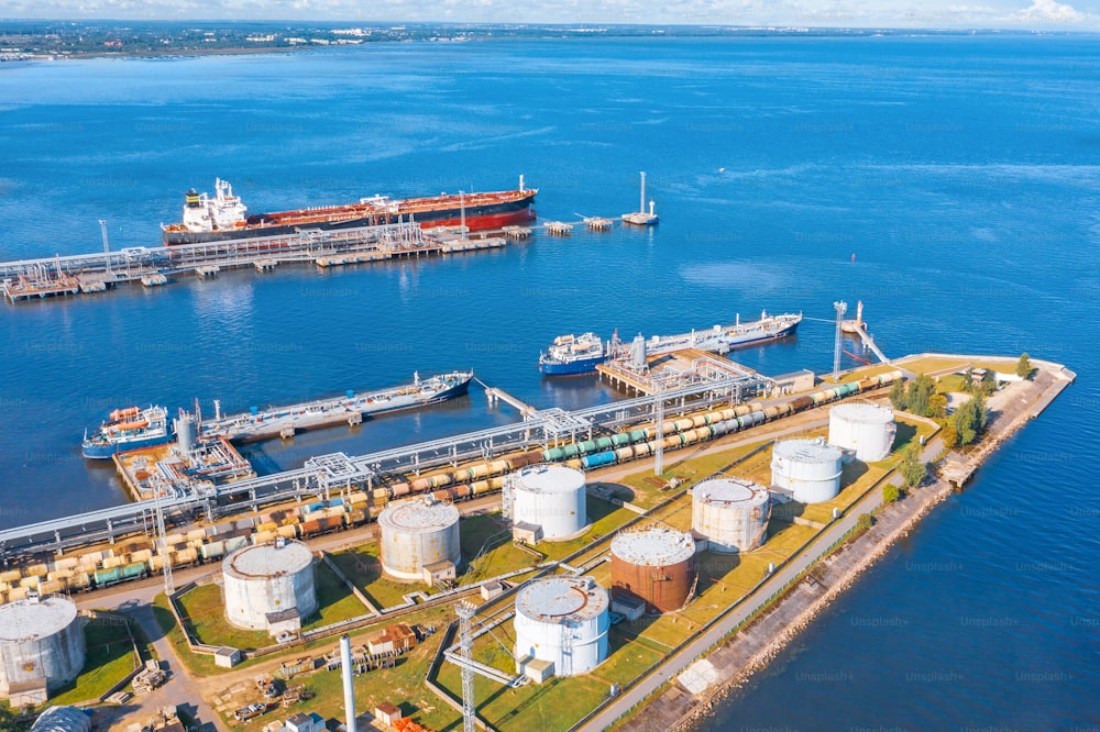 Aerial view large port oil loading terminal with large storage tanks. Railway infrastructure for the delivery of bulk cargo by sea, using pump station in ship tanker for transportation and delivery