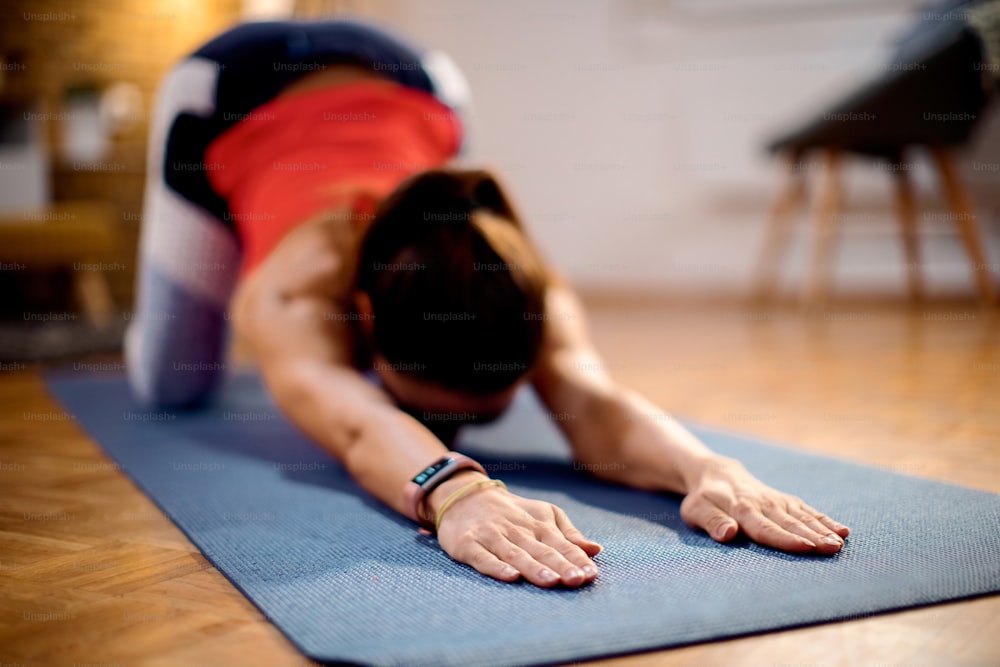 Close-up of sportswoman doing stretching exercises while working out at home.