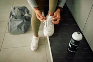ジムの更衣室でスニーカーに靴紐を結ぶアスリートの接写。