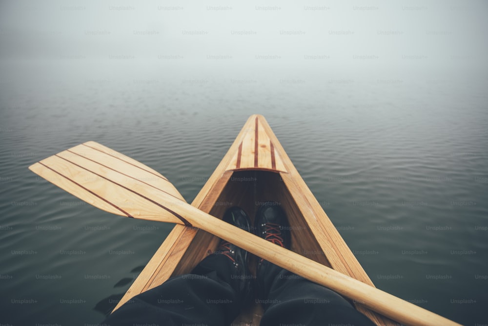 Prua della canoa sul lago nebbioso, visuale in prima persona.