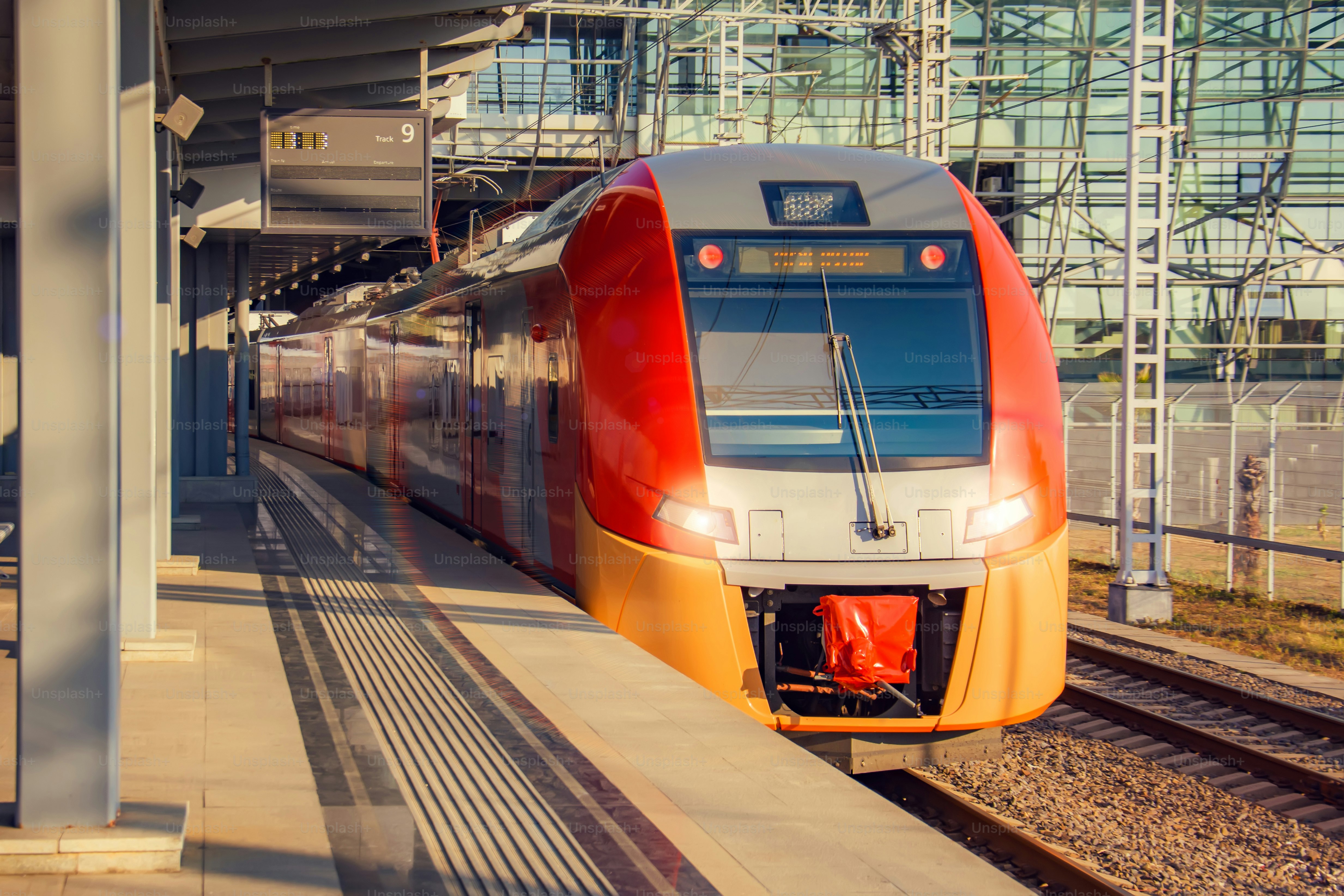 Suburban modern train at railway station at the stop of an empty passenger platform