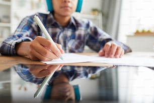 Close-up of digital tablet on the table with child sitting and making notes in notebook in the background