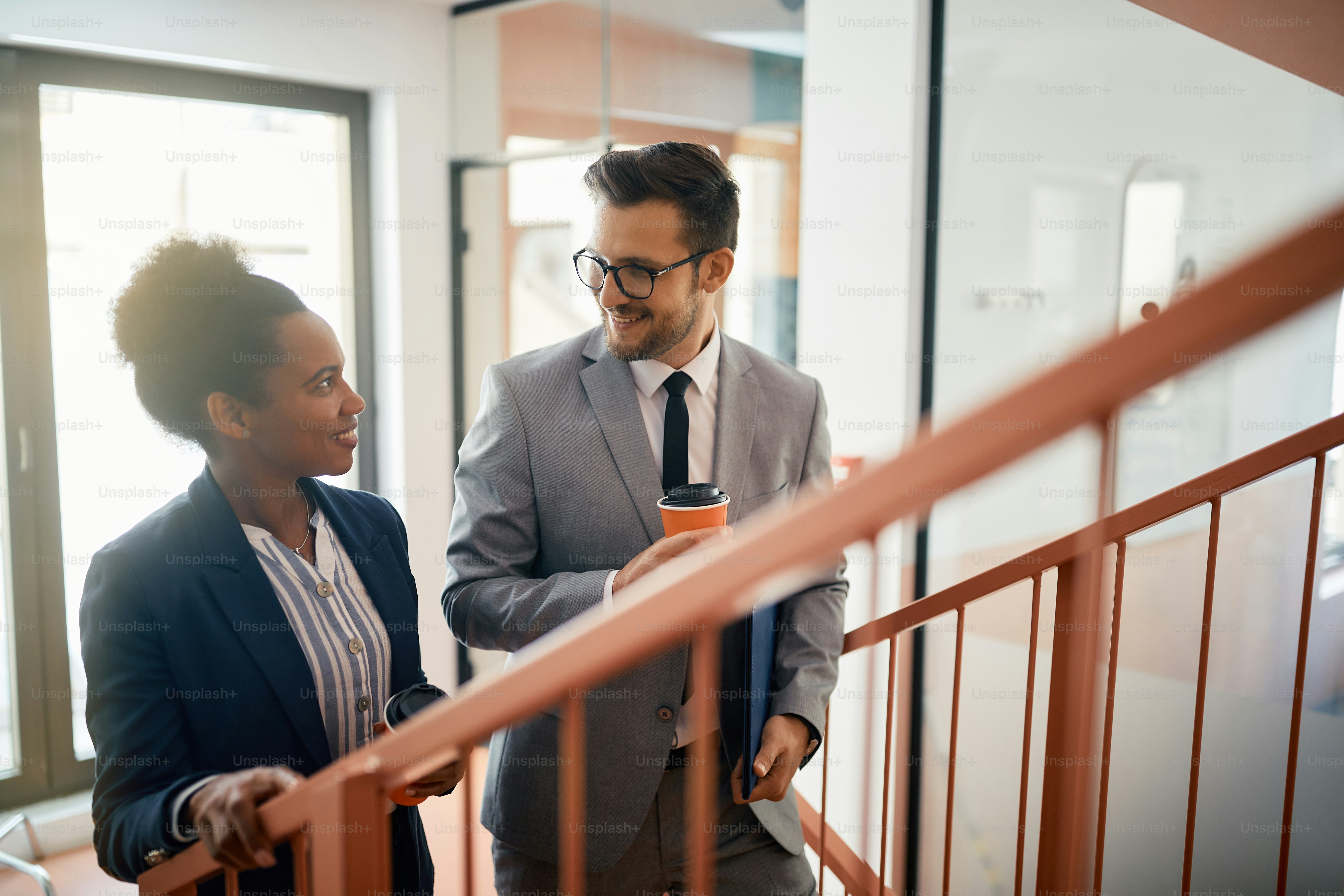 Happy African American businesswoman and her coworker communicating during their coffee break at work.