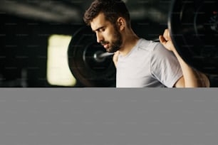 Male athlete exercising with barbell during strength training in a gym.