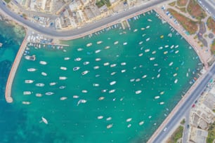 Aerial top view small boats in the bay azure water, city bay, marina and promenade with road and houses