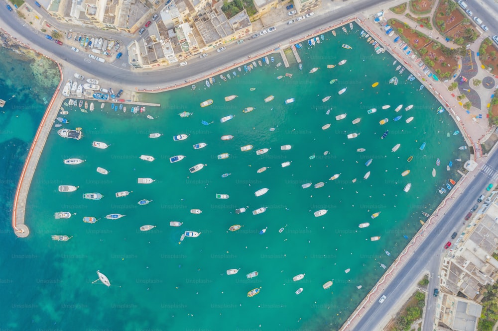 Aerial top view small boats in the bay azure water, city bay, marina and promenade with road and houses
