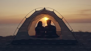 海辺のキャンプ場のテントに座る男女