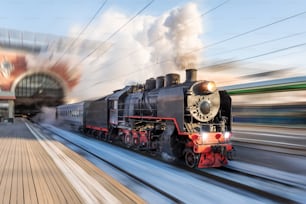 Il vapore della locomotiva con potenti nuvole di fumo lascia la stazione per una velocità di movimento di viaggio retrò