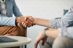 Primer plano de compañeros de trabajo dándose la mano durante una reunión de negocios en la oficina.