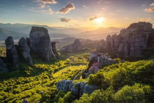 Puesta de sol sobre el monasterio de Rousanou y el monasterio de San Nicolás Anapavsa en el famoso destino turístico griego Meteora en Grecia al atardecer con rayos de sol y destellos de lente