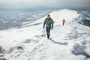 Dois caminhantes subindo sobre o cume nevado da montanha.