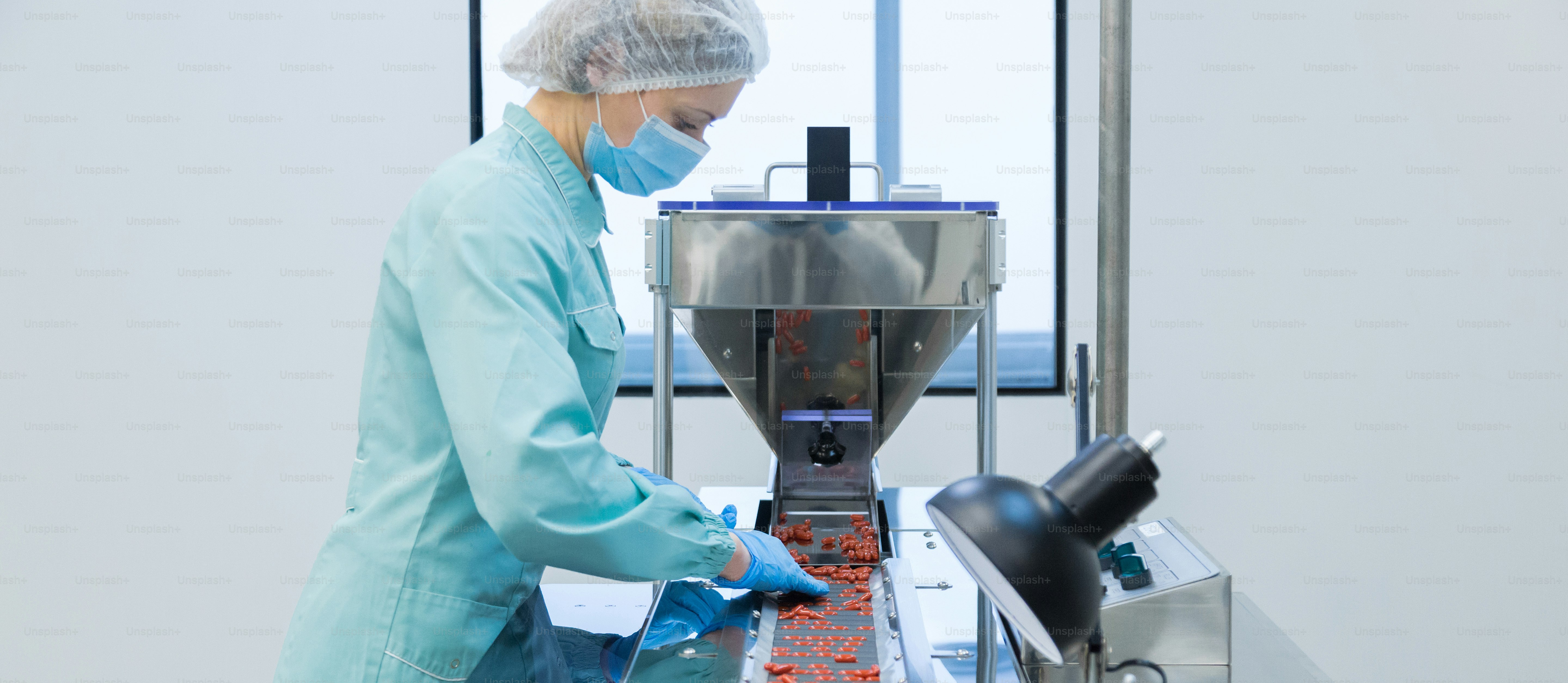 Técnico farmacéutico en ambiente estéril trabajando en la producción de píldoras en una fábrica de farmacia