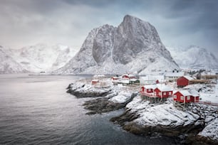 Famous tourist attraction Hamnoy fishing village on Lofoten Islands, Norway with red rorbu houses. With falling snow in winter on sunrise