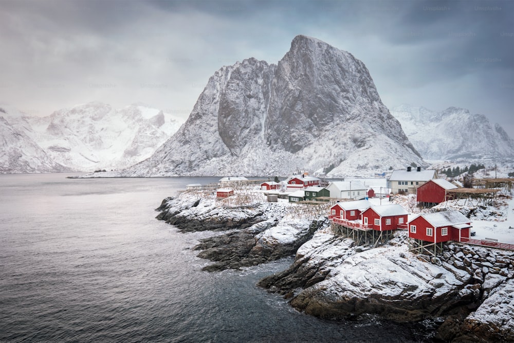 노르웨이 로포텐 제도의 유명한 관광 명소 함노이 어촌 마을에는 빨간 로르부 주택이 있습니다. 일출에 겨울에 눈이 내리는 것과 함께