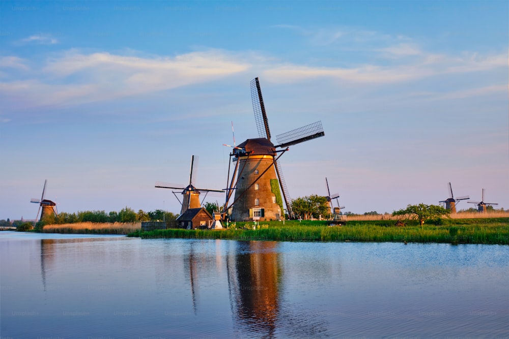Niederländische ländliche Landschaft mit Windmühlen am berühmten Touristenort Kinderdijk in Holland bei Sonnenuntergang mit dramatischem Himmel