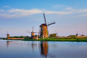 Paisaje rural de los Países Bajos con los molinos de viento en el famoso sitio turístico Kinderdijk en Holanda en la puesta del sol con el cielo dramático