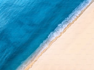 Aerial view of an idyllic sea sandy beach with an incoming azure wave. The concept of holidays in tropical countries and relaxation. Background for travel and vacation